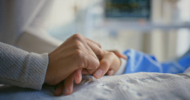 A carer holding a patient's hand