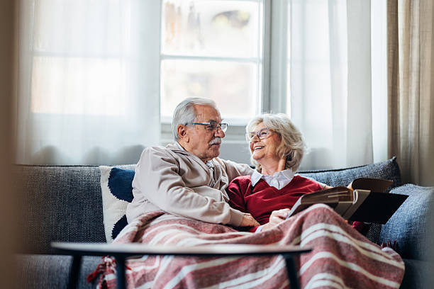 An older couple laughing together on a sofa at home